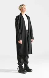 Sacón largo de corte regular, confeccionado en tela simil paño color gris oscuro. Presenta diseño abierto, mangas largas con terminaciones al corte y bolsillos laterales ocultos.