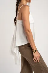 Blusa blanca de satén, corte al cuerpo con escote en V y tirantes finos. Presenta un diseño cruzado en los laterales con tiras largas para atar.
