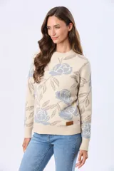 Buzo tejido en jacquard con estampado floral en tonos azul y marrón sobre base color crema. Presenta cuello redondo y puños acanalados.