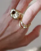Anillo dorado con forma irregular y un agujero en el centro.