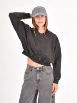 Campera tipo bomber de corte cropped, color negro con efecto lavado, cierre frontal completo y puños elásticos.
