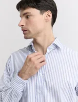 Camisa celeste y blanca a rayas verticales, de manga larga y corte clásico.