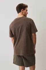 Remera de calce relajado y cuello redondo, color verde musgo con efecto lavado, y pequeño bordado de un morrón en el pecho.