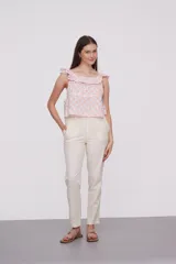 Blusa de algodón con estampado geométrico en tonos rosado y blanco, diseño holgado con escote bote y detalle de volados en los hombros.