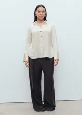 Camisa de corte clásico con acabado satinado, cuello camisero, cierre frontal con botones y manga larga con puños abotonados.
