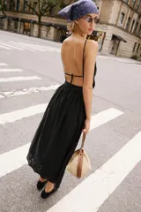 Vestido midi negro de escote recto con tirantes finos ajustables, espalda descubierta y falda amplia con bajo de bordados perforados a tono y detalle de puntilla.