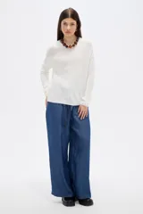 Sweater de tejido de punto fino en color blanco, con cuello redondo a la base y mangas largas de corte holgado.