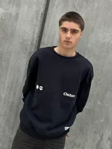 Buzo negro de corte holgado con cuello redondo y puños y bajo acanalados. Estampado frontal con un sol y la palabra "Osten" en blanco.