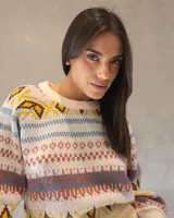 Sweater de tejido de punto con diseño nórdico y geométrico multicolor sobre base color crema. Presenta cuello redondo, mangas largas amplias con puños ajustados y un calce relajado.
