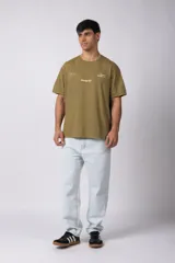 Remera de algodón con efecto lavado gastado, cuello redondo y mangas cortas. Presenta estampados minimalistas en el frente con el logo de la marca y la frase 'Local Based, Global Attitude'.
