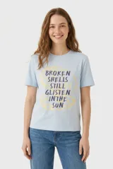 Remera celeste de manga corta con cuello redondo y estampa frontal de una concha marina con texto en inglés.