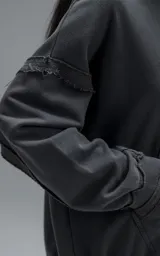 Hoodie oversize de algodón con efecto desgastado, costuras expuestas y roturas decorativas. Presenta capucha, bolsillo frontal tipo canguro y terminaciones deshilachadas.