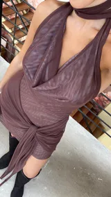 Vestido corto de microtul color marrón, con escote tipo buche y cuello halter. Presenta un diseño con superposición de tela en la falda que crea un efecto drapeado con un lazo lateral largo.