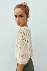 Top cropped de punto con diseño combinado de texturas, cuello redondo y mangas cortas amplias. Presenta una estructura calada con detalles de cintas verticales.
