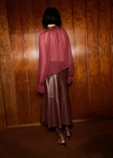 Blusa de viscosa color bordó, con diseño semitransparente, cuello drapeado con adorno de fular y mangas largas con puños elásticos.