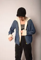 Campera azul de jean con interior de corderito blanco, cierre frontal y bolsillos laterales.