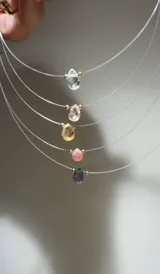 Gargantilla de tanza transparente con dije de piedra semipreciosa en forma de lágrima y separadores dorados.