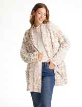 Cardigan abierto de tejido soft, marca Ruby Rd., con patrón de arabescos en relieve en tonos beige y blanco. Tiene cuello solapa fluido, mangas largas de corte recto y bolsillos aplicados en la parte delantera.
