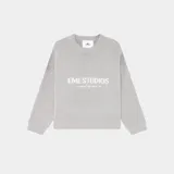 Suéter de punto grueso color gris, con corte holgado y ligeramente corto. Presenta cuello redondo, puños y ruedo acanalados, con el logo de la marca y la frase 'curated by ben ice' tejidos en jacquard en el frente.