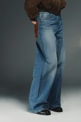 Jeans de tiro alto con corte wide leg y pernera recta. Presentan un diseño de cinco bolsillos con efecto lavado y cierre frontal mediante cremallera y botón metálico.