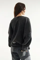 Buzo oversize de corte unisex, color rojo con efecto desgastado (acid wash), confeccionado en algodón con interior de polar. Presenta costuras frontales decorativas, hombros caídos, mangas largas con puños elastizados, rib en el cuello y el ruedo, y un pequeño logo bordado en el pecho.