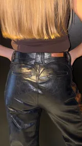 Pantalón de cuero negro con paneles laterales de cuero invecchiato con efecto desgastado. Presenta un diseño de cordones laterales a lo largo de las piernas y ajuste en la cadera, con corte recto y ligeramente acampanado.