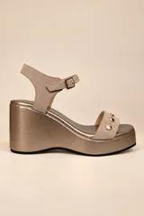 Sandalias de plataforma con cuña, confeccionadas en cuero negro con punta cuadrada y plantilla metalizada. Tienen una tira delantera decorada con tachas metálicas redondas y una tira al tobillo con hebilla regulable.