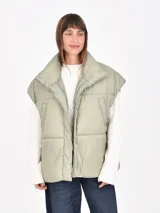 Chaleco puffer color verde oliva, con cuello alto y cierre frontal de broches a presión.