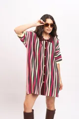 Vestido camisola de tejido de punto fresco con rayas verticales en tonos fucsia, verde oscuro, beige y rosado. Presenta cuello polo marrón, mangas cortas y cierre frontal con botones de madera.