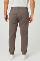 Pantalón tipo babucha de corte ajustado, confeccionado en tejido de algodón color gris topo. Presenta cintura elástica con cordón ajustable, bolsillos laterales y puños elásticos en los tobillos.