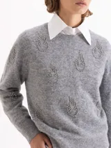 Sweater de tejido de punto gris con textura de pelo, cuello redondo y mangas largas. Presenta un bordado frontal de piedras brillantes con forma de flamas.