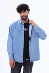 Camisa de jean de manga larga en tono azul claro, con cuello clásico, cierre frontal con botones y dos bolsillos delanteros con solapa.