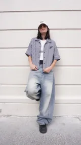 Camisa de corte boxy fit confeccionada en algodón con estampado de cuadros vichy en blanco y negro. Presenta un diseño gráfico artístico en color negro y blanco en la parte posterior.