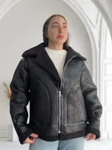 Campera negra de cuero sintético con interior de piel sintética color negro, corte oversize, cuello solapa y cierre frontal con cremallera.