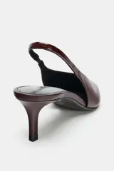 Zapato destalonado de tacón medio fino, confeccionado en piel con acabado texturizado. Presenta un diseño de punta fina y una tira trasera con pieza elástica para mayor ajuste.