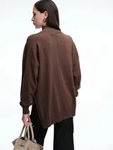 Sweater de tejido de punto color marrón, con cuello alto, corte amplio y tajos laterales en el ruedo. Presenta una costura vertical central en el frente y mangas largas con puños acanalados.