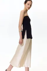 Pollera midi de tiro alto, color beige, confeccionada en tela satinada de caída suave con acabado brillante y leve vuelo en el bajo.