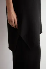 Top asimétrico negro de un solo hombro, con diseño holgado y dobladillo irregular.