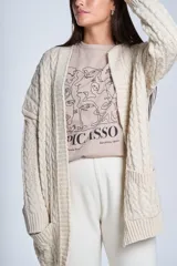 Cárdigan negro tejido con diseño de ochos, corte holgado y bolsillos frontales.