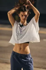 Camiseta deportiva blanca de tejido ligero y ventilado, con diseño holgado y espalda recortada envuelta.