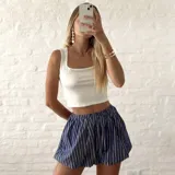 Pollera corta estilo globo, color azul marino con rayas verticales blancas, con cintura elástica.