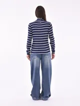 Polera blanca con rayas horizontales negras, cuello alto y mangas largas.