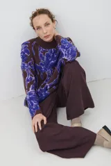 Buzo de tejido de punto con diseño floral en contraste, cuello redondo y mangas largas. Presenta una textura suave y un corte holgado.