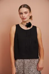 Blusa de cuello redondo y sin mangas, color negro, con diseño más largo en la parte trasera.