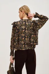 Camisa de manga larga con estampado paisley en tonos negros, amarillos y rosados. Presenta volados en los hombros, puños con terminación en volado y cierre frontal con botones.