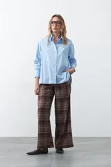 Camisa de corte relajado y diseño clásico, confeccionada en tela de algodón color celeste. Presenta cuello tradicional, cierre frontal con botones y mangas largas con puños rectos.