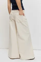 Pantalón denim de corte wide leg, tiro alto y color crudo con costuras en contraste.