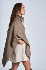 Poncho tejido color beige, con cuello alto y corte asimétrico.