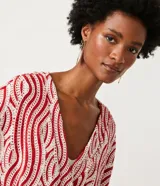 Cárdigan largo de punto con estampado geométrico en tonos rojo y blanco, manga larga, lazo en la cintura y abertura frontal sin botones.