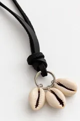 Collar de diseño artesanal con cordón negro regulable y dijes de caracoles cauri naturales.